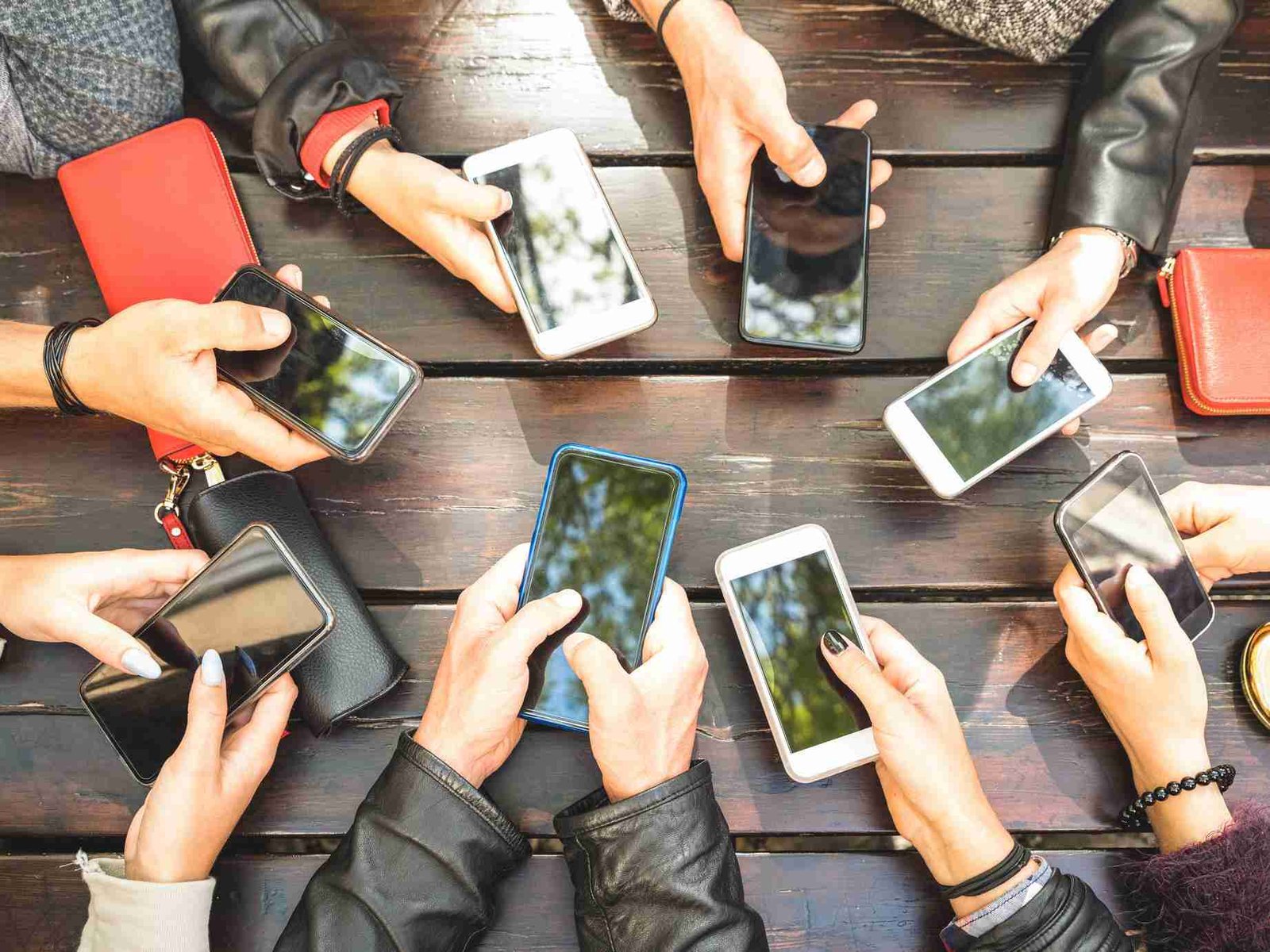 Group of friends gathered around a table, all engaging with their smartphones. phones with no credit check