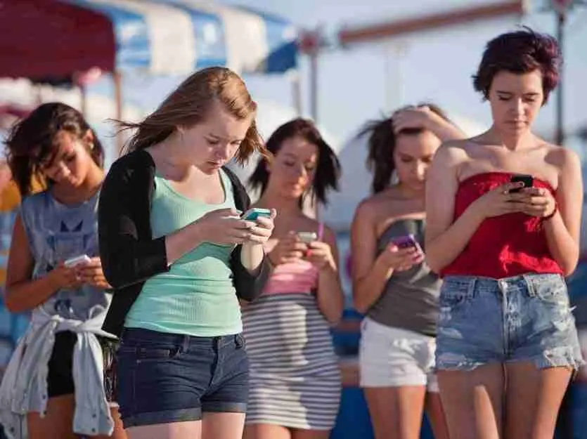 A group of young people absorbed in their contract phones for bad credit no upfront fees, seemingly oblivious to their surroundings.
